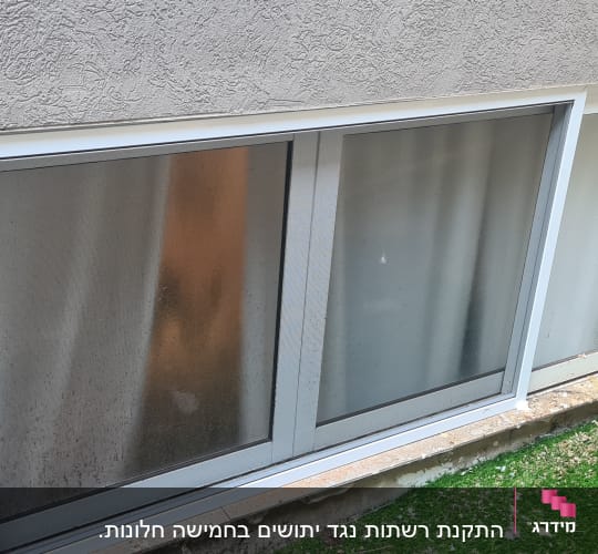 חלון אלומיניום עם מסגרת לבנה בקיר חיצוני